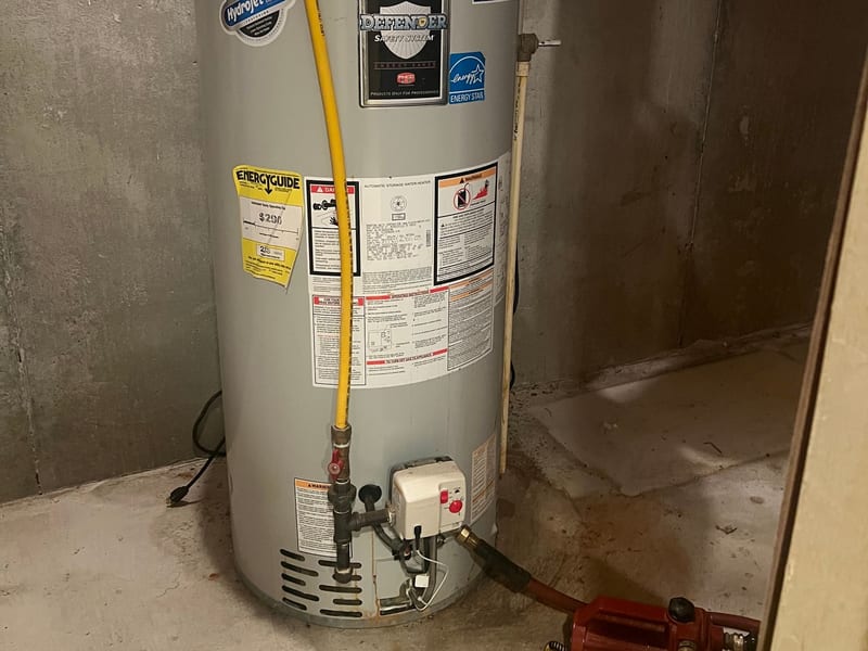 Gas water heater with a power vent, a small expansion tank and a yellow gas line in a basement