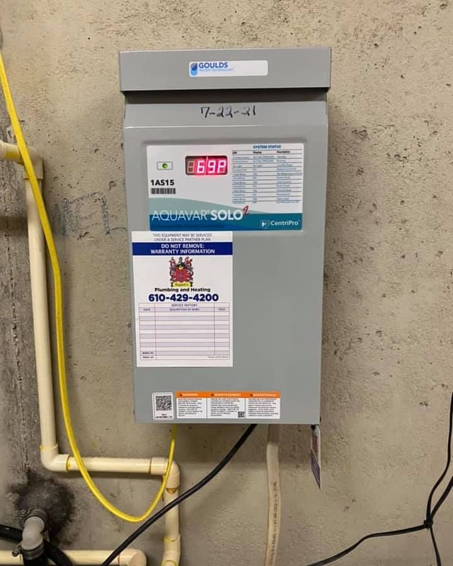 Aquavar Solo pump control panel on a concrete wall with a yellow gas line, white piping and a service sticker with the phone number